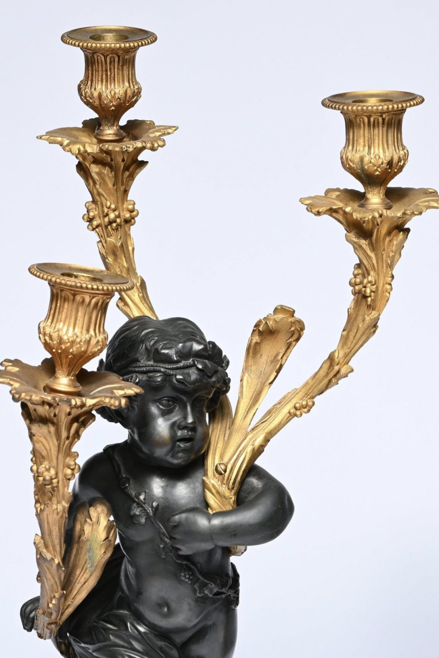 An Exceptional Pair of French Louis XVI Style Patinated and Gilt Bronze Three-Light Candelabra, after Clodion. Circa 1830.